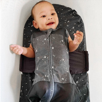 Happy baby with arms out in Charcoal Stars SNOO Sack on Charcoal Galaxy SNOO Sheet in SNOO
