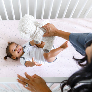Toddler happy grabbing for SNOObear on DreamBreeZzz Crib Matttress