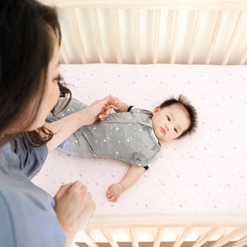 Baby in Lola Crib on Rose Galaxy Crib Sheet with mom