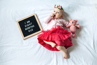 8-month-old baby girl posing in front of letterboard that says "I am eight months old"