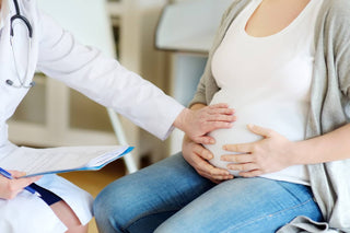 A doctor feels a pregnant person's belly at a checkup.