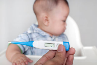 Digital thermometer being held in front of a baby boy