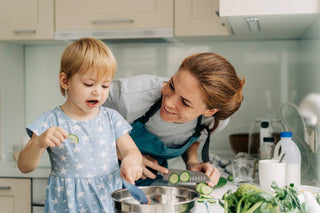 mom cutting veggies with toddler in kitchen