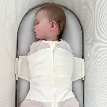 Baby swaddled sleeping on a gray silk SNOO Sheet in the SNOO bassinet.