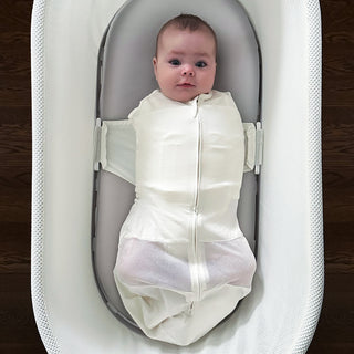 Baby wrapped in an ivory swaddle on a gray Silk SNOO Sheet in SNOO.