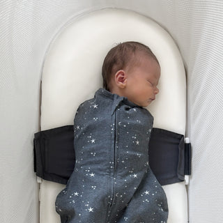 Baby sleeping in SNOO on an Ivory Silk SNOO Sheet wearing a charcoal gray SNOO Sack featuring star patterns.