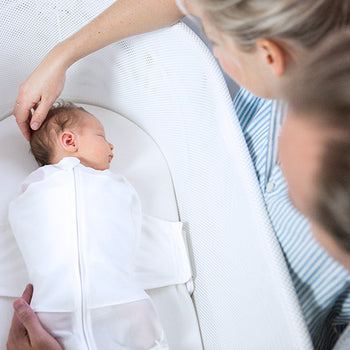 Mom holding sleeping baby's head in Ivory SNOO Sack on Ivory SNOO Sheet in SNOO