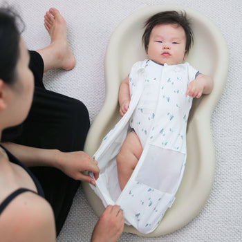 Baby unzipped in Ivory Pine Sleepea on changing pad