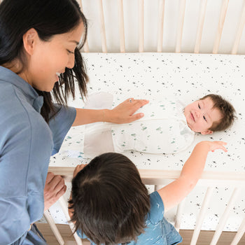 Baby in Sleepea Swaddle on DreamBreeZzz Crib Mattress with mom and sister