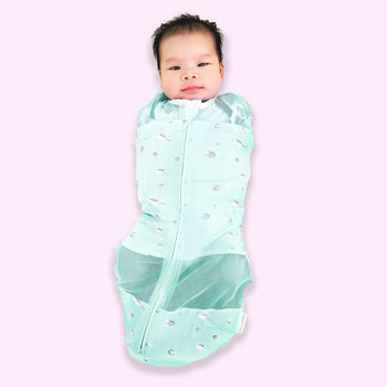 Baby in zipped-up teal planets Sleepea swaddle sack