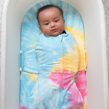 Baby swaddled in Rainbow Tie-Dye SNOO Sack in SNOO